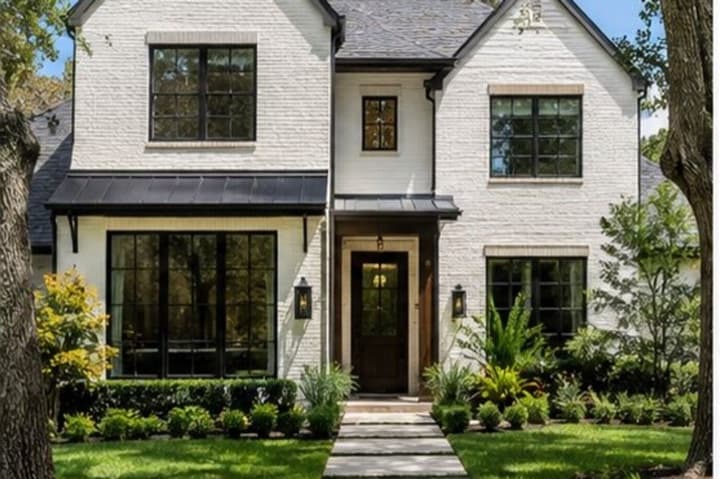 White brick two-storey home with black window frames and a landscaped front garden